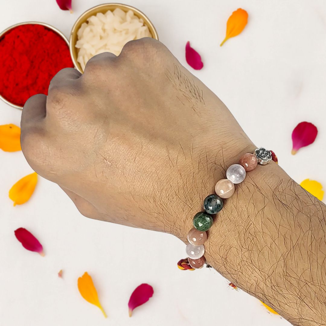 Hand wearing a beaded rakhi with colorful petals on a white background