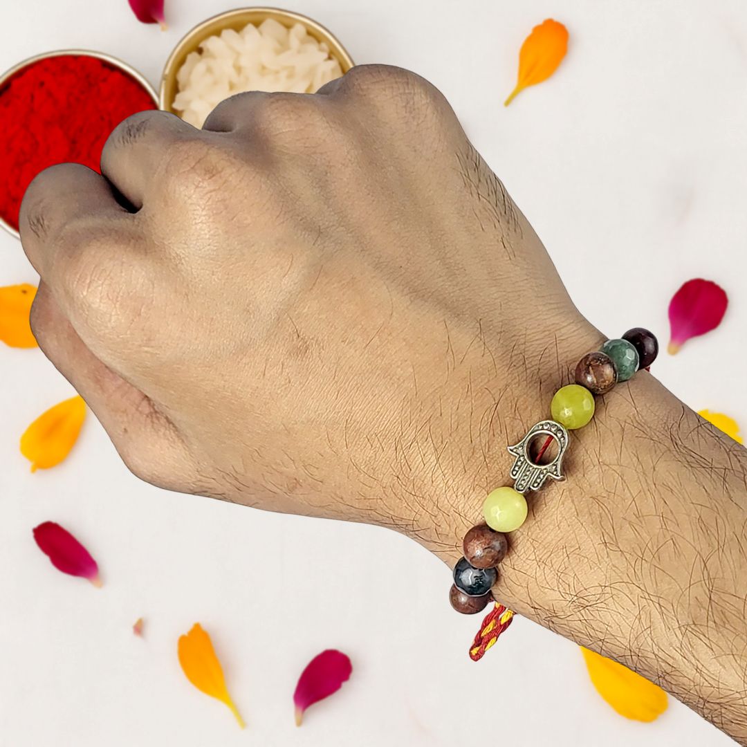 Hand wearing a colorful beaded rakhi with petals on a white background