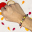 Hand wearing a colorful beaded rakhi with petals on a white background