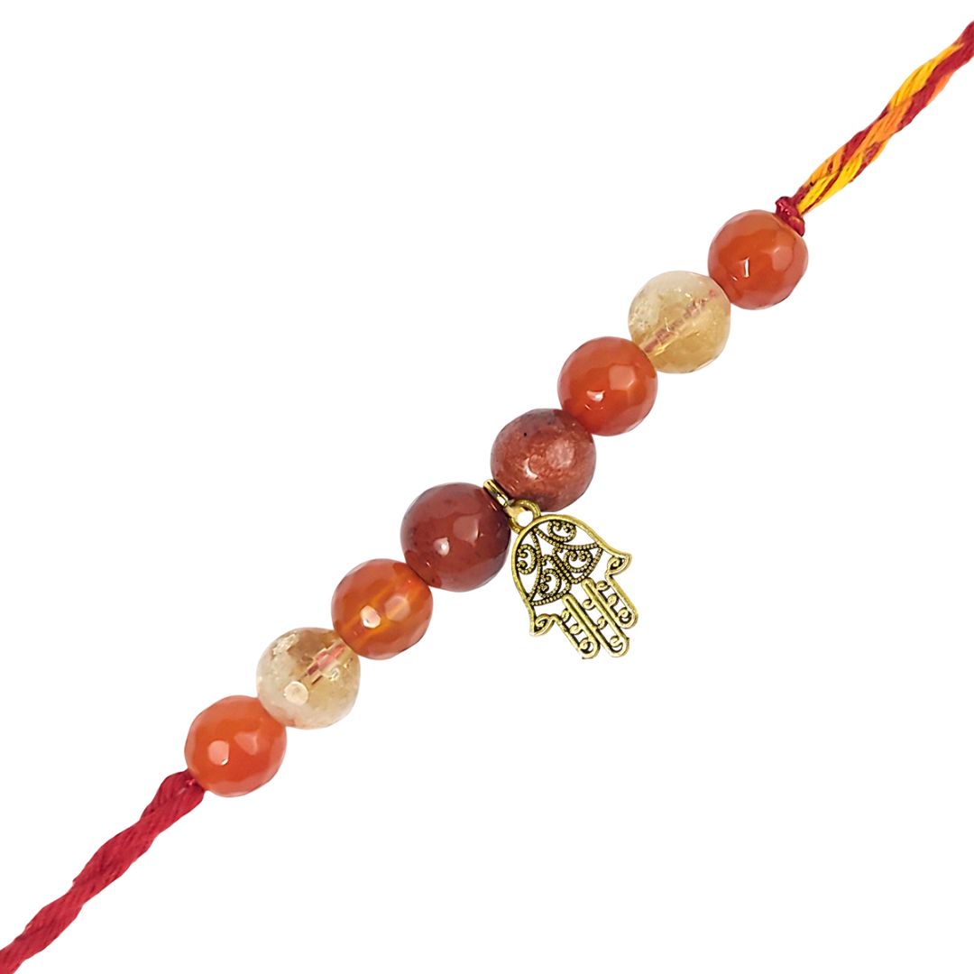 Beaded rakhi with a gold Hamsa hand charm on a white background