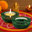 Two green candle holders with lit candles on a colorful fabric background with decorative elements.