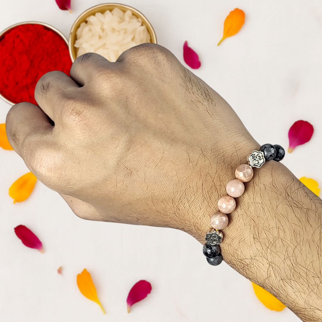 Hand wearing a beaded rakhi with colorful petals on a white background