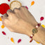 Hand wearing a rakhi with decorative elements on a white background with colored petals.