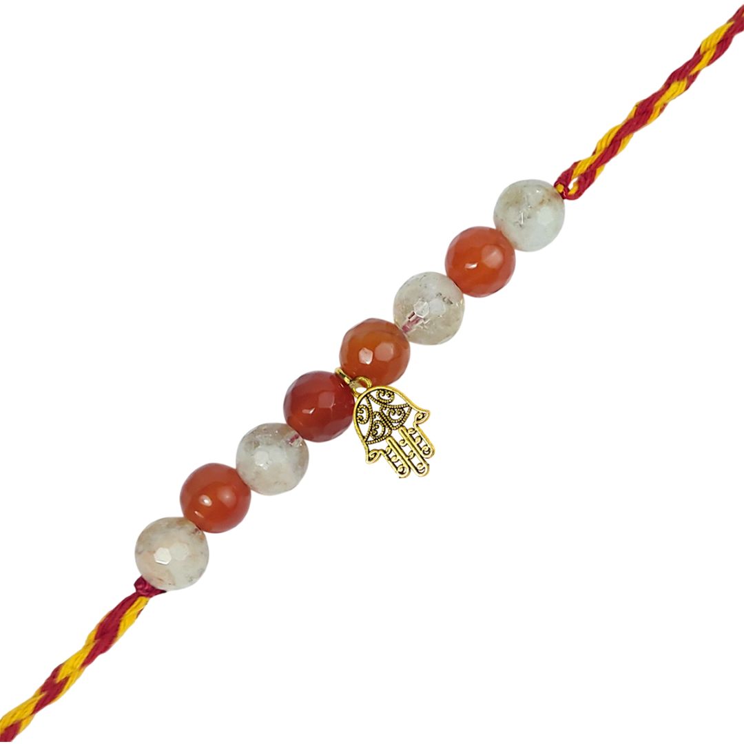 rakhi with red and white beads and a gold Hamsa charm on a white background