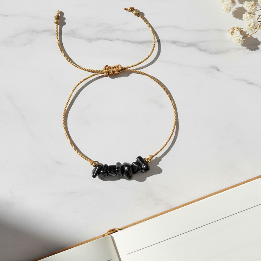 thread bracelet with black beads on a marble surface