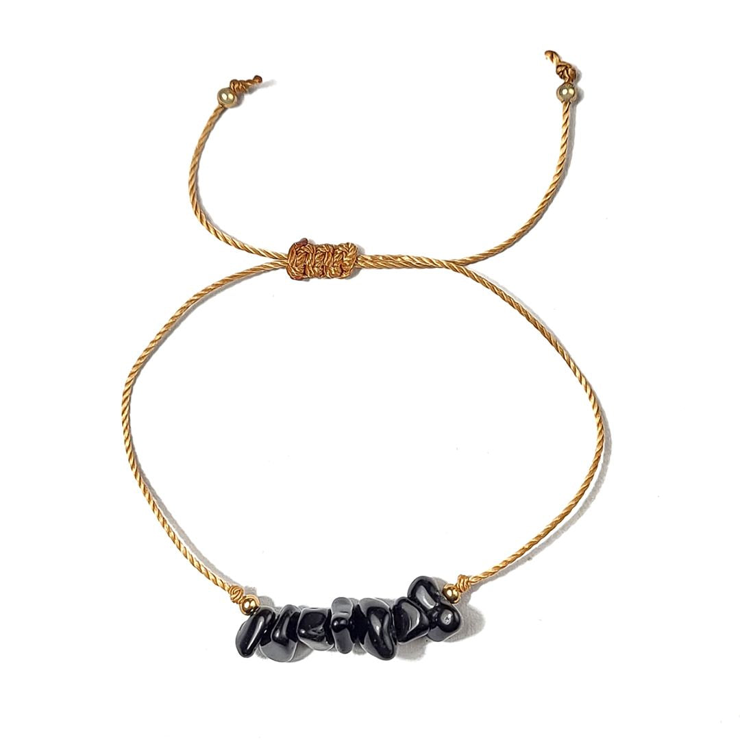 golden thread bracelet with black beads on a white background