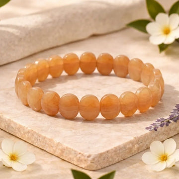 Orange beaded bracelet on a light wooden surface with flowers