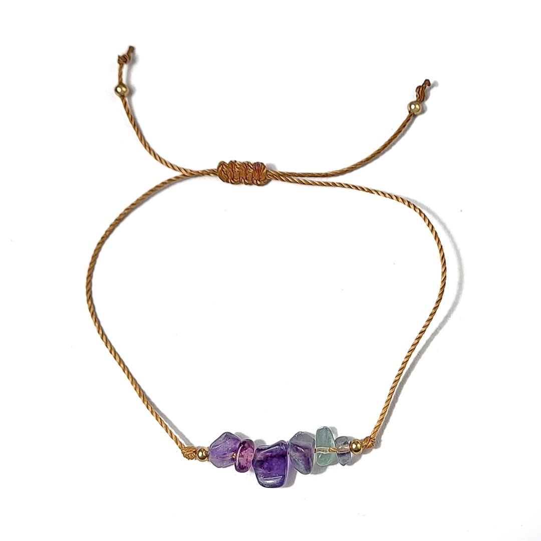 thread bracelet with purple and green beads on a white background