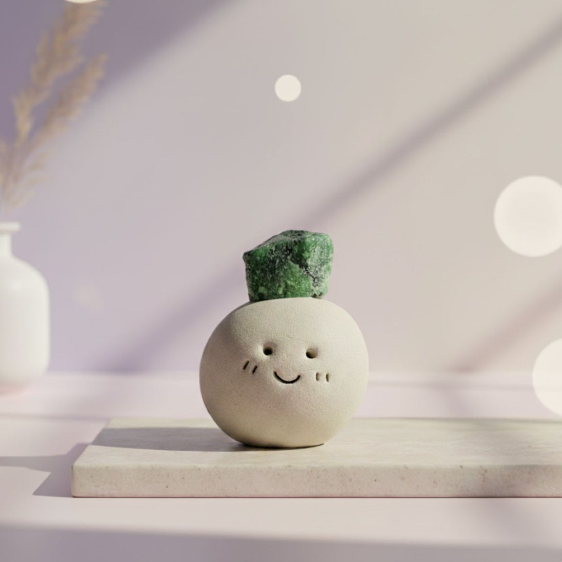 Ceramic smiley face vase with a green crystal on top, placed on a light surface with a soft, blurred background.