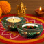 Decorative candle holders with a lit tea light candle on a colorful mat with a ganesha statue and marigold flowers in the background.