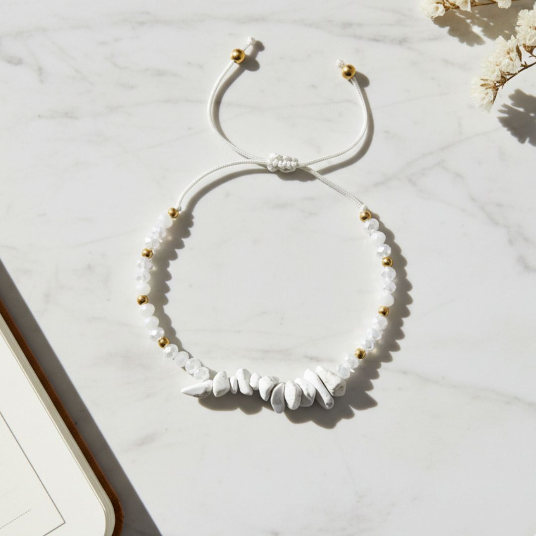 White beaded thread bracelet with gold accents on a light marble surface