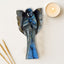 Decorative blue color angel sculpture with a candle and wooden skewers on a light surface