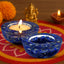 Two blue decorative candle holders with lit candles on a colorful fabric background.