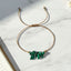thread bracelet with malachite green stone beads on a marble surface