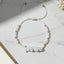 moonstone beaded thread bracelet with white stones and gold accents on a marble surface