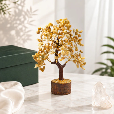 Yellow jasper crystal tree with mustard-yellow stone chips on a wooden base, beside a gift box