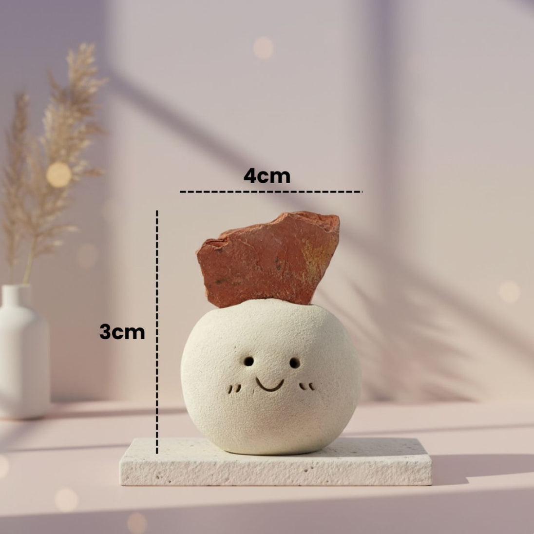 Small decorative red stone with a smiley face and measurements on a neutral background