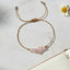 bracelet with pink stone beads and gold thread on a marble surface