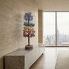 Decorative tree on a marble ledge with a cityscape view through large windows.