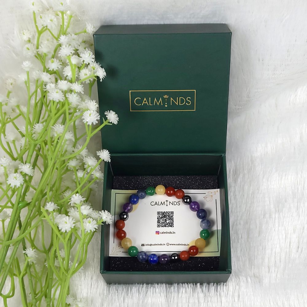 Colorful beaded bracelet in a 'CALMINDS' box with flowers on a white background