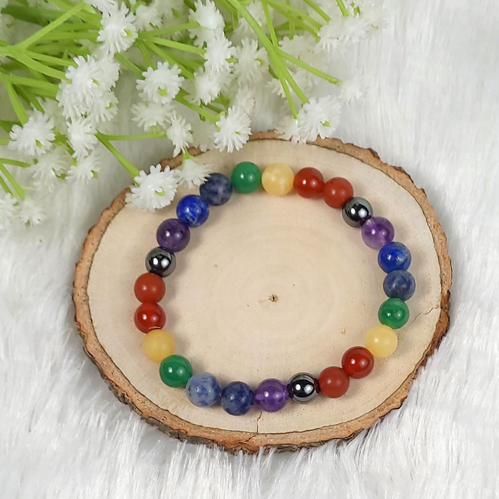 Multicolored beaded bracelet on a wooden slice with white flowers in the background