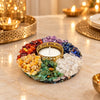7 Chakra Tea Light Holder lit on a marble table beside gold diyas and a brass tray