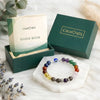 Colorful beaded bracelet on a white stand with 'Calminds' branded box and guidebook in the background.