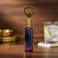 Decorative bottle opener with purple and gold design on a wooden surface.