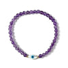 Purple beaded bracelet with a gold and silver evil eye charm on a white background