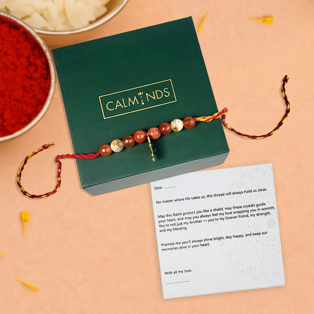 Rakhi with a message card and Calminds box on a peach background