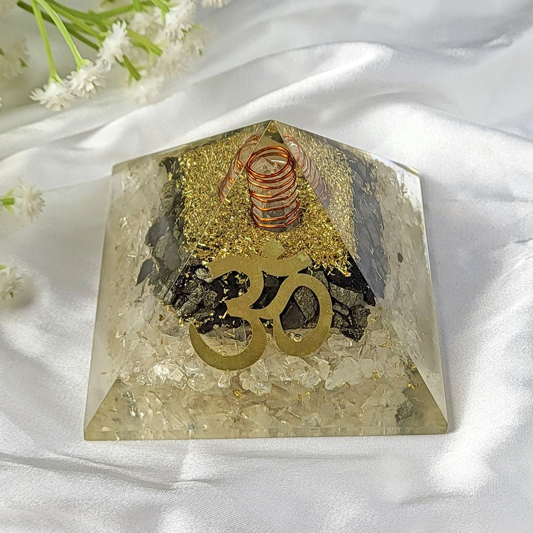 Crystal pyramid with 'Om' symbol on a white fabric background