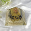 Crystal pyramid with 'Om' symbol on a white fabric background