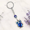 Keychain with owl design and blue evil eye charm on a light background