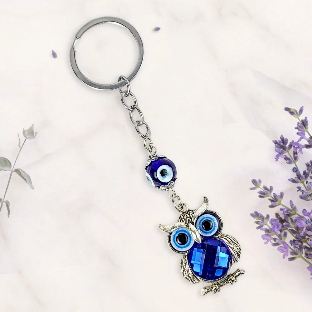 Keychain with owl design and blue evil eye charm on a light background