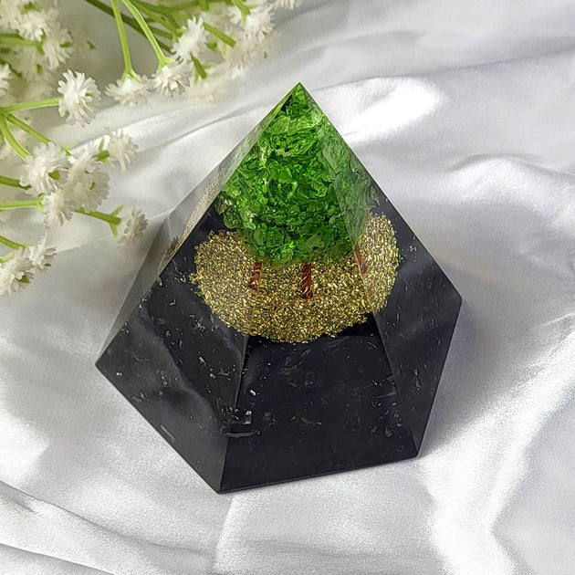 Pyramid-shaped object with green and gold interior on a white fabric background