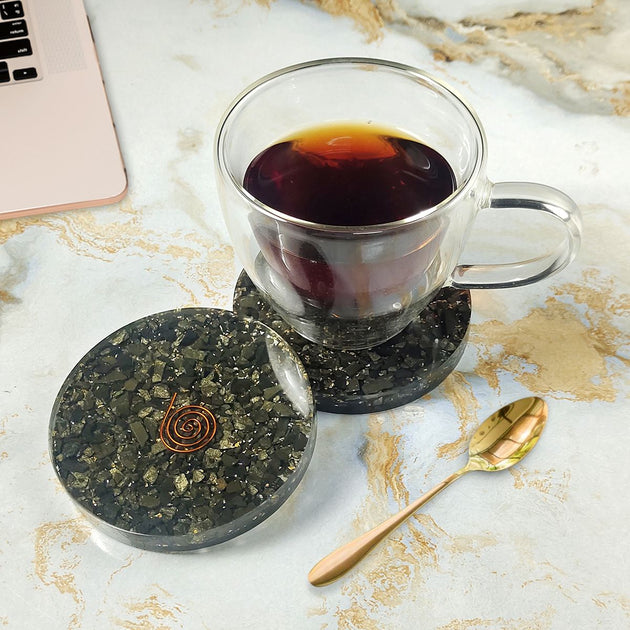 Clear glass mug with dark liquid on a marble surface with a gold spoon and coaster.