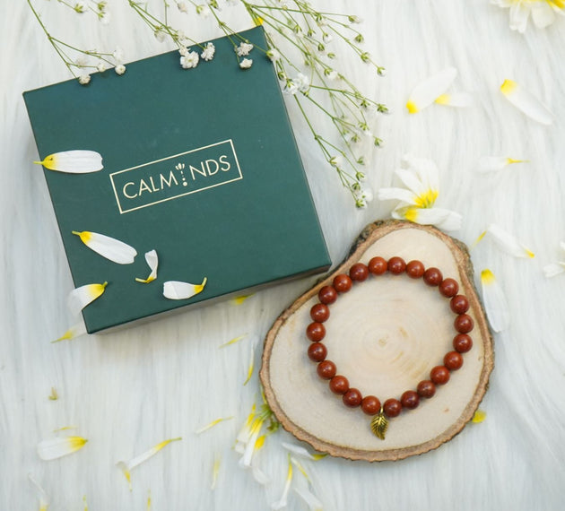 Red Jasper Healing Bracelet with a golden leaf petal next to calminds box