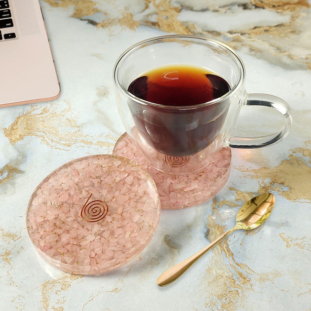 Clear mug with pink base and lid on a marble surface with a laptop.