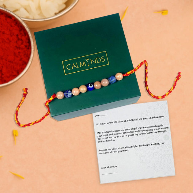 Colorful beaded rakhi with a message card on a green box, set against a beige background.