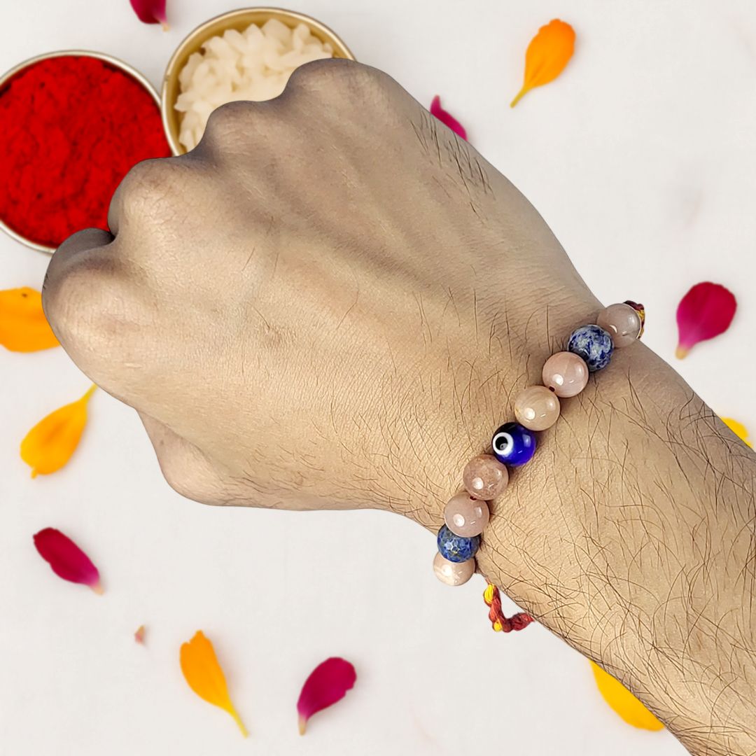 Hand wearing a beaded rakhi with colorful petals on a light background
