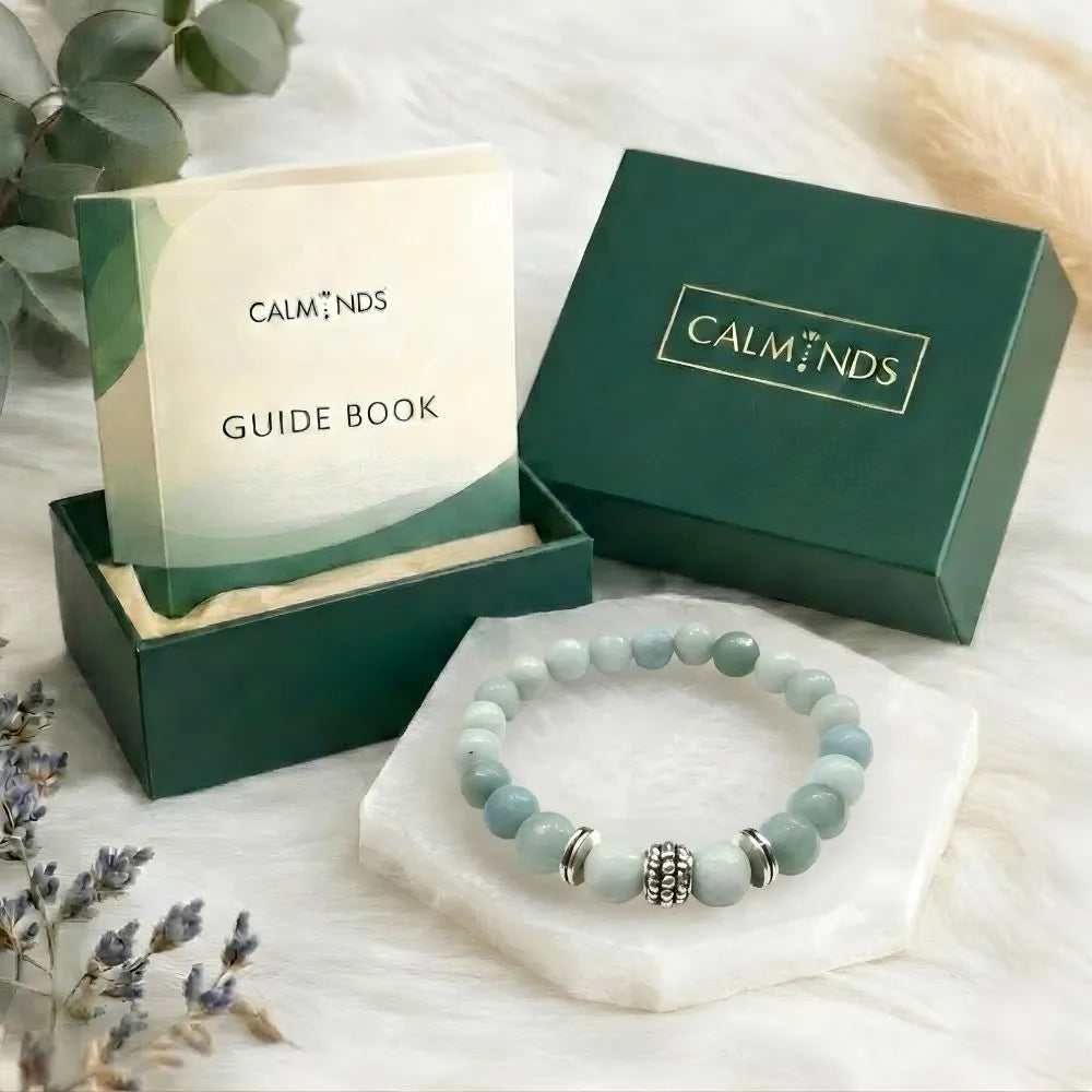 Pink bracelet with silver accents on a white stand, surrounded by 'Calminds' branded items.