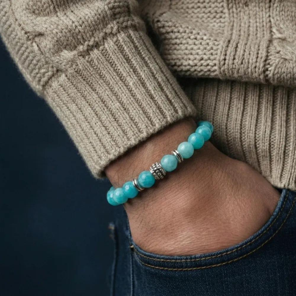 Turquoise beaded bracelet on a wrist with a beige sweater and dark background