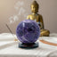 shiny purple amethyst crystal ball on black tourmaline stand