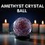 Amethyst crystal ball with candles in the background on a dark background