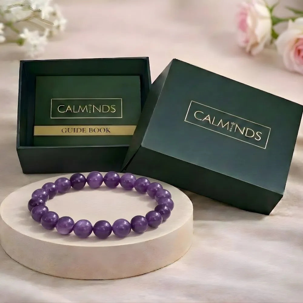 Purple beaded bracelet on a white stand with 'Calminds' branded box and guide book in the background.