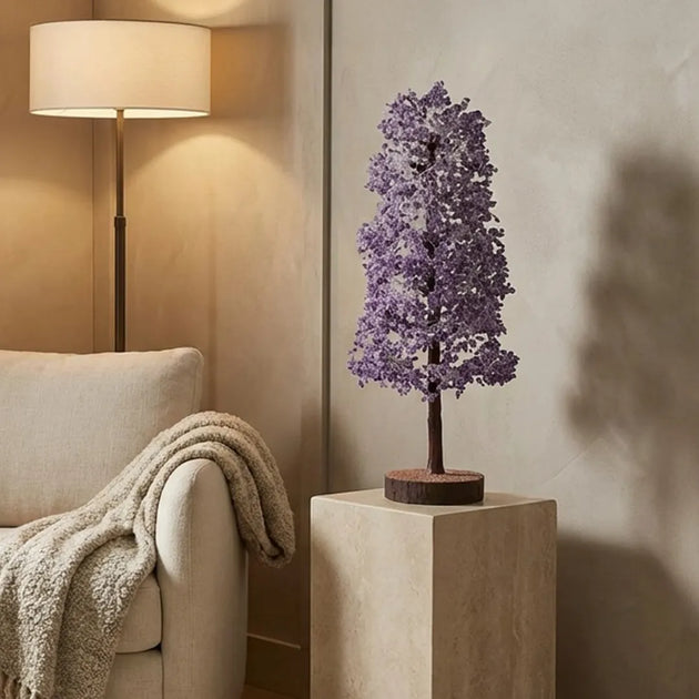 Decorative purple tree lamp on a pedestal in a living room setting with a beige armchair and lamp.