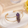 Gold bracelet with a purple crystal on a white plate