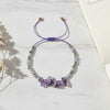 Purple beaded thread bracelet on a light surface with a blurred background