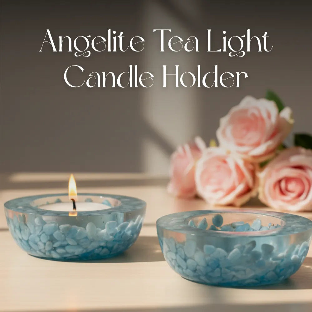 Two blue glass tea light candle holders with a lit candle and pink roses on a blurred background.