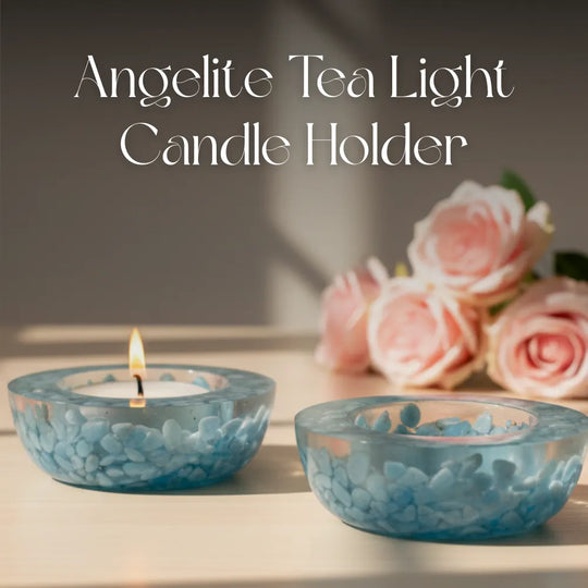 Two blue glass tea light candle holders with a lit candle and pink roses on a blurred background.